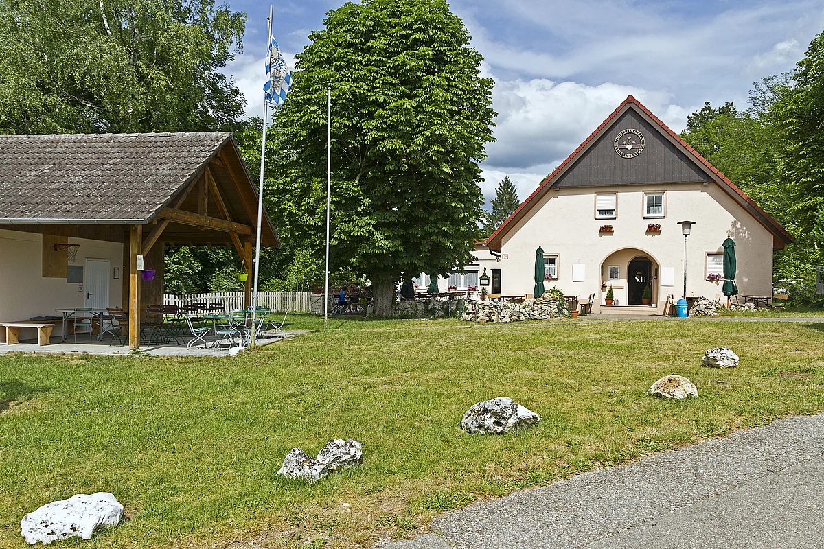 Das Naturfreundehaus von außen mit Hütte rechts und grüner Wiese im Vordergrund.