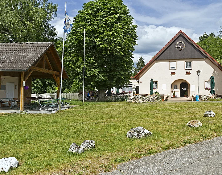 Das Naturfreundehaus von außen mit Hütte rechts und grüner Wiese im Vordergrund.