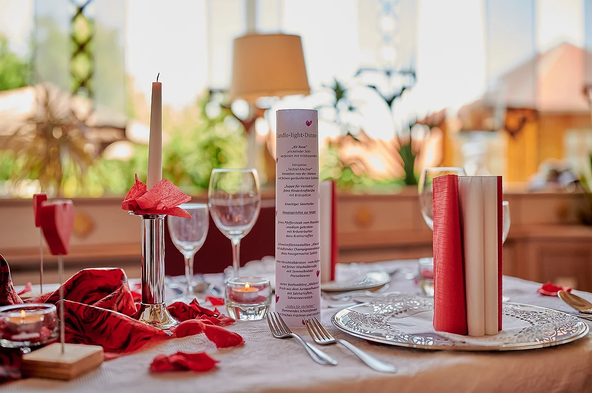 Candle-Light-Dinner im Landhotel "Zur Jurahöhe" Romantisch gedeckter Tisch mit Kerze, Weingläsern und roter Dekoration bei Tageslicht.